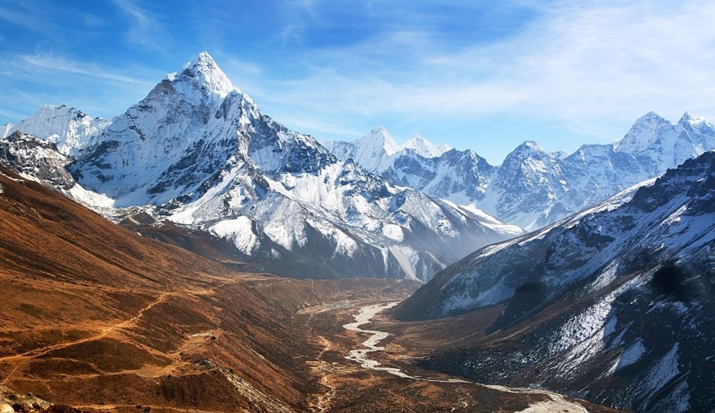 High-altitude Himalayan mountain range with snow-crested summits, mist, and cloud forest valley